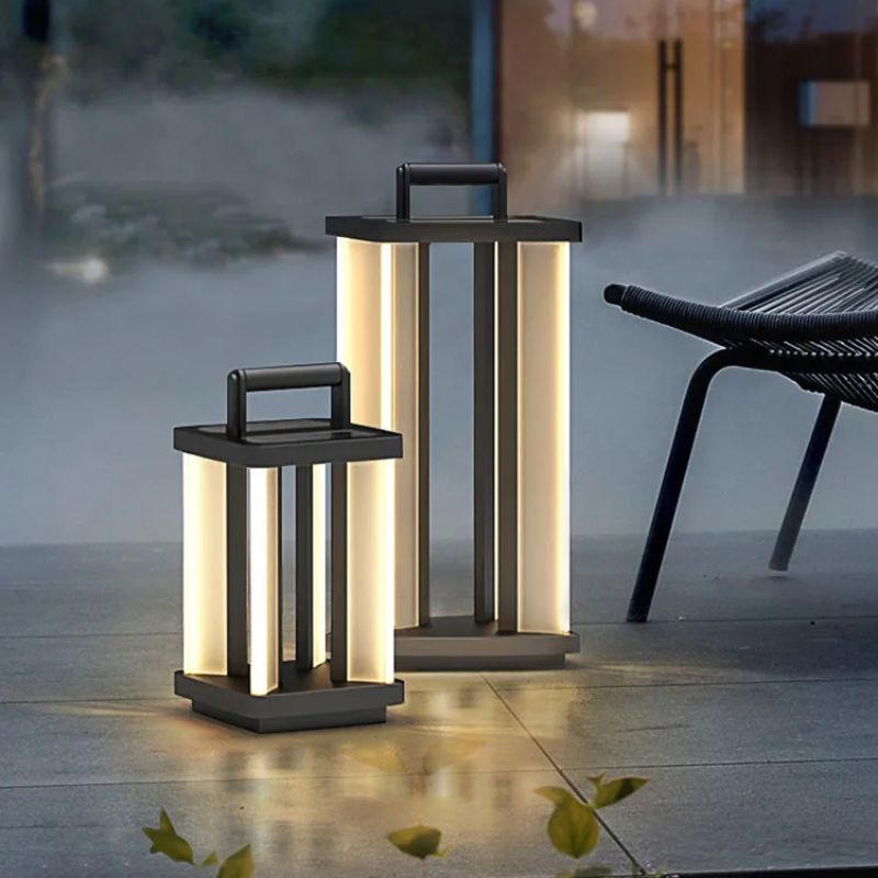 Two illuminated "Villa Solar Lamps" of different sizes stand on a stone patio at dusk or dawn, with a black outdoor chair partially visible in the background.