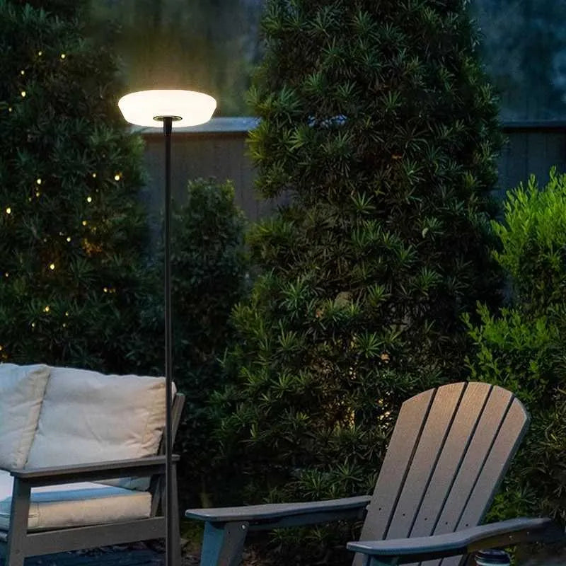 Outdoor setting with a lamp post and Adirondack chairs in a garden at night.