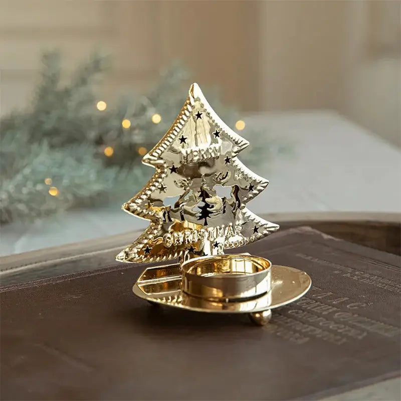 A single golden Christmas tree-shaped tea light holder sitting on a dark book.