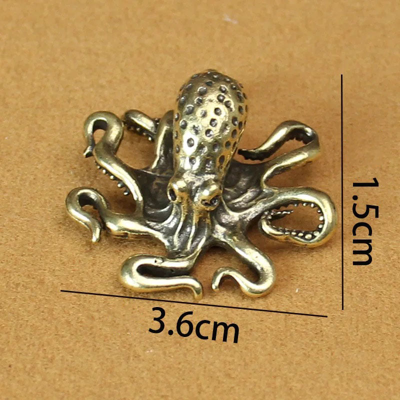 A brass octopus figurine with intricate detailing, placed on a brown surface with labeled dimensions of 3.6 cm in length and 1.5 cm in height.