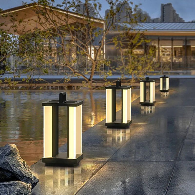 Four illuminated "Villa Solar Lamps" line a wet stone pathway near a shallow body of water and modern buildings at dusk or dawn.