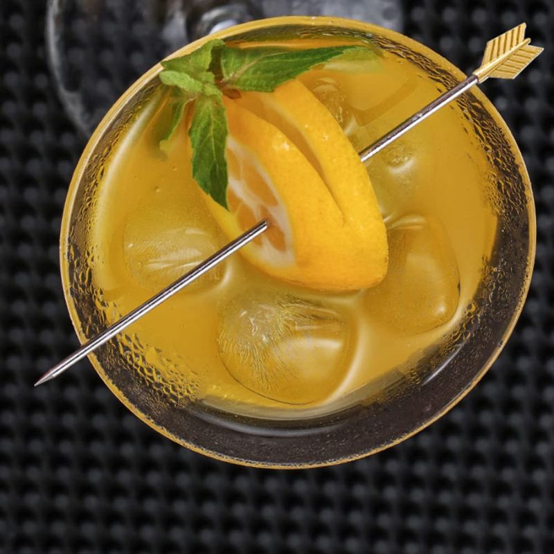 Yellow cocktail with lemon, mint, and an arrow-shaped gold cocktail pick.