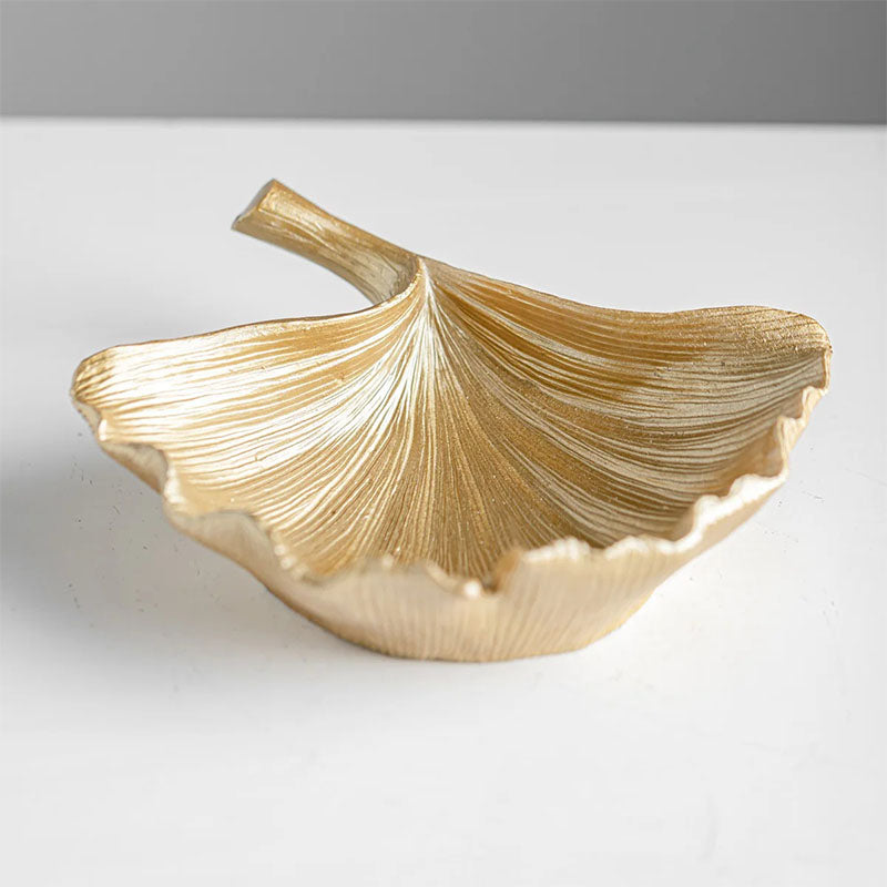 Gold-colored decorative bowl shaped like a ginkgo leaf, featuring intricate vein details and an elegant, organic form.