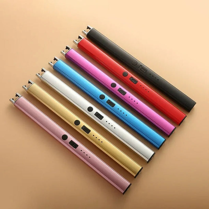 Seven slim, cylindrical electric arc lighters in various colors (black, red, pink, blue, white, gold, and light pink) arranged diagonally on a light brown surface. Each lighter has a small button and indicator lights.