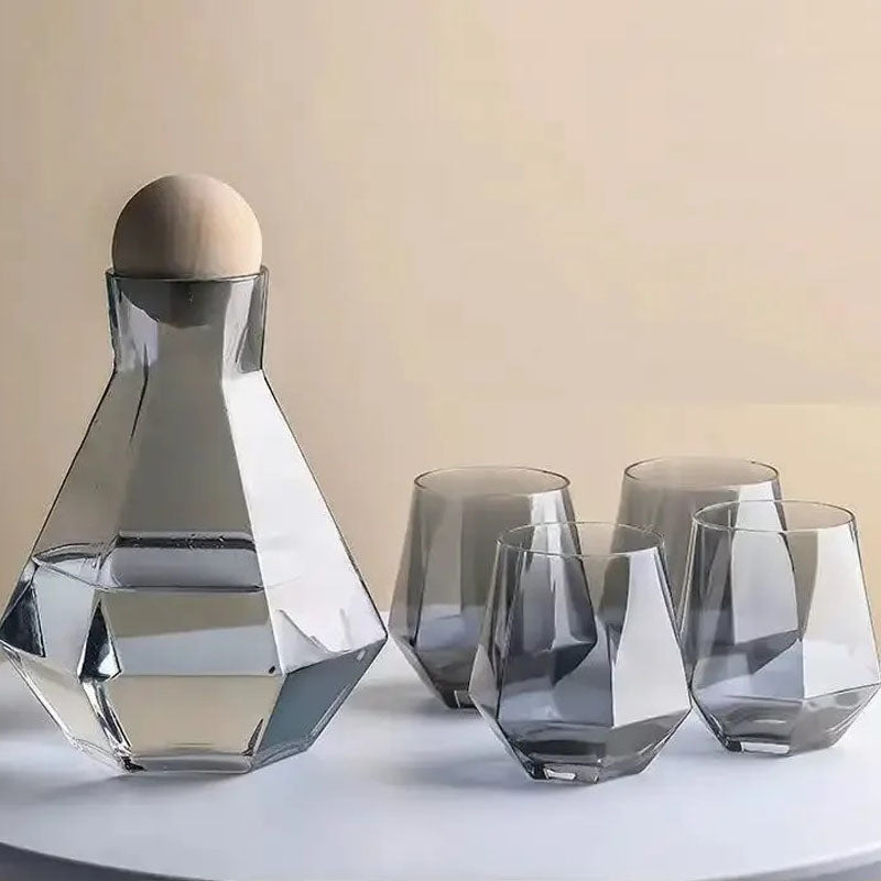 Gray tinted glass pitcher and four matching faceted glasses on a light surface. The glass has a smoky gray appearance.