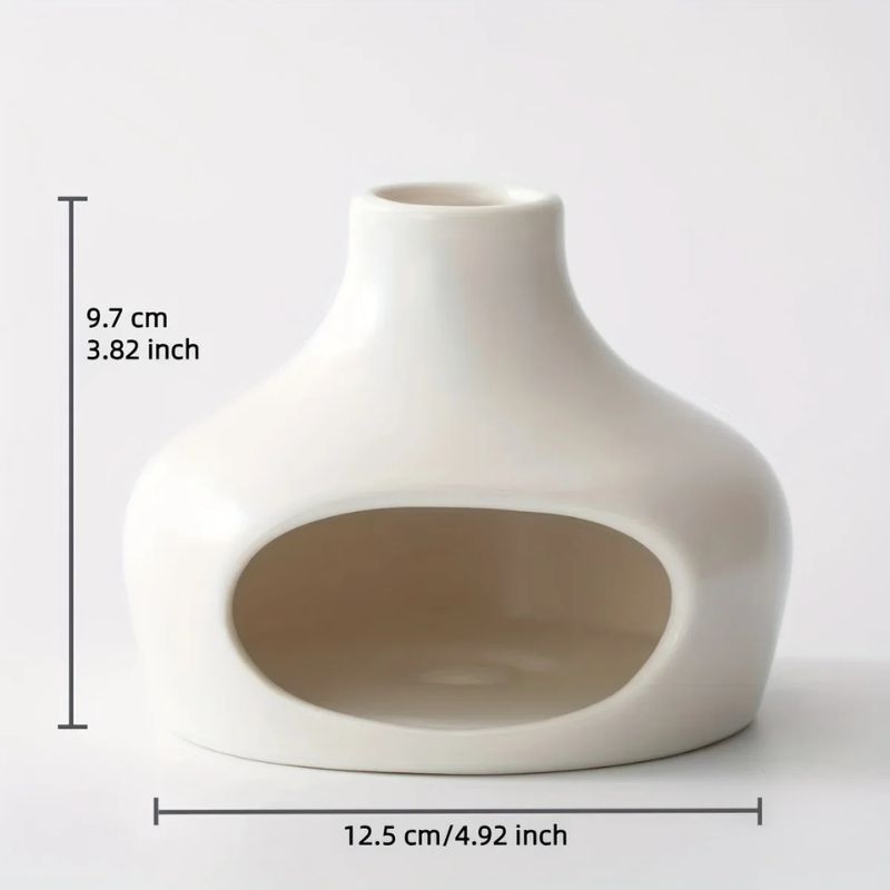 A small, white ceramic hideout with a smooth, rounded shape. It has an open front entrance and a narrow top opening. The dimensions are marked on the image, indicating a height of 9.7 cm (3.82 inches) and a width of 12.5 cm (4.92 inches). The background is plain white.