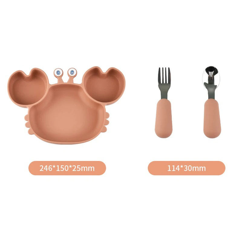 A three-piece baby feeding set is shown against a white background. The set includes a light brown silicone plate shaped like a crab with two compartments, and a matching silicone-handled fork and spoon. Dimensions are provided below each item: the plate is 246 x 150 x 25 mm, and the utensils are 114 x 30 mm.