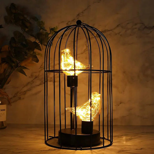Decorative lamp with birdcage design and glowing bulbs on a wooden surface.