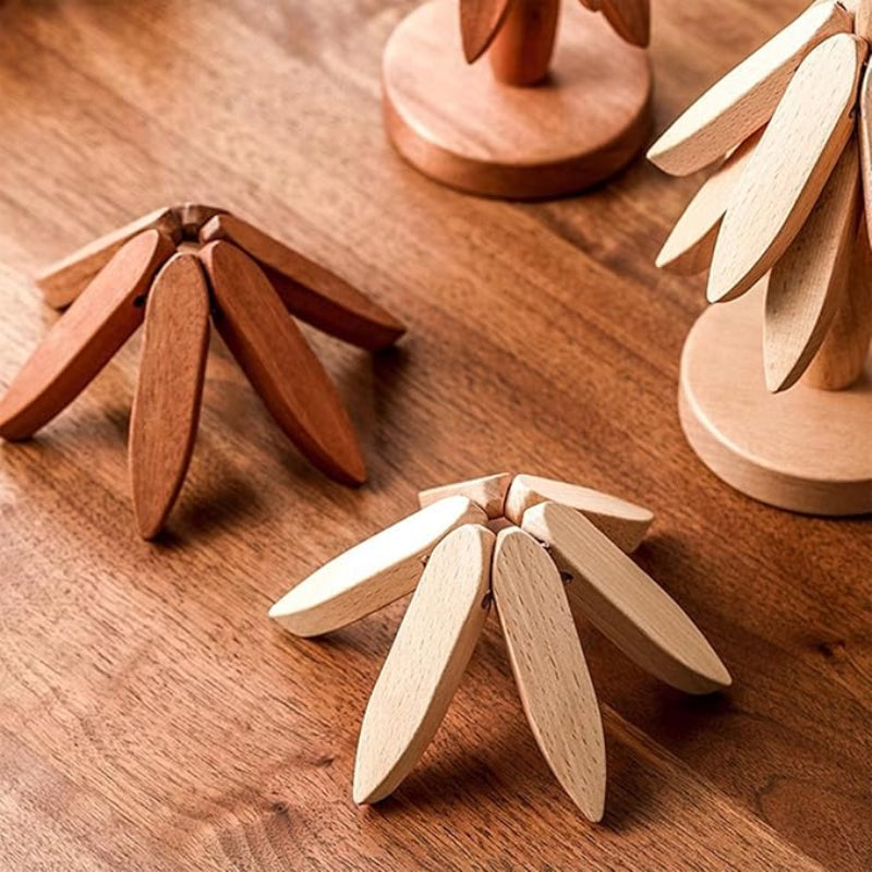 Three wooden trivets, two tree-shaped (one light, one dark) and one flat dark one, are on a wooden surface.