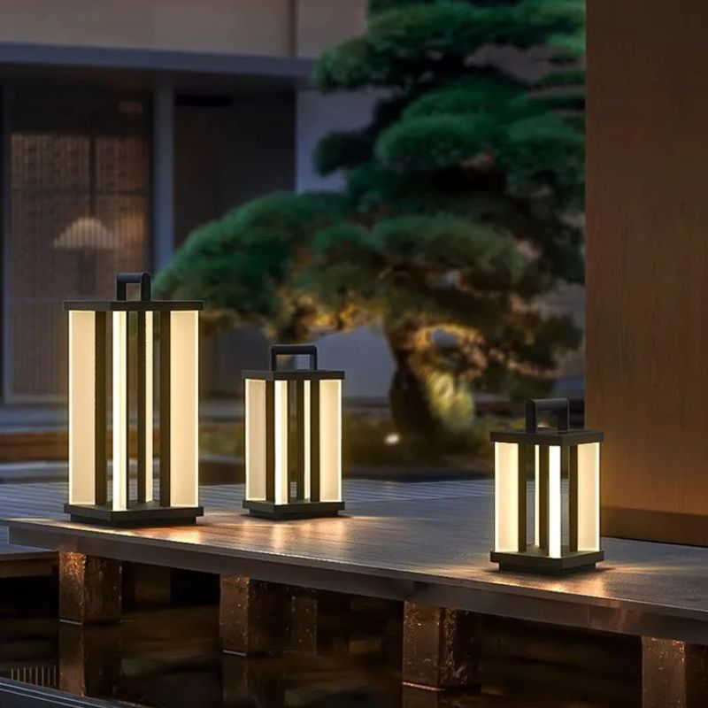 Three illuminated "Villa Solar Lamps" of different sizes are placed on a dark wooden surface, possibly a bridge or walkway over water, at night.