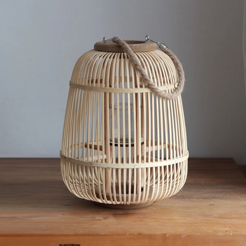 Tall woven bamboo lantern with a sturdy rope handle and glass candle holder, offering a rustic yet elegant touch to any space.