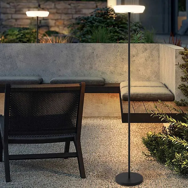 Outdoor patio setting with a table, chairs, and a standing lamp on a stone patio.