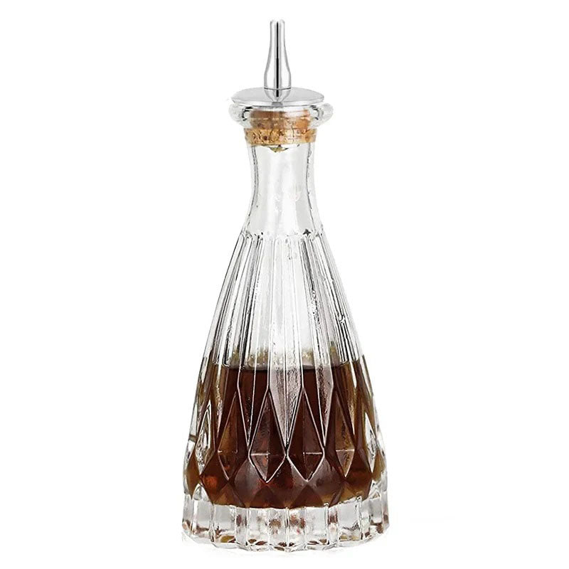 This bottle has a unique tapered shape, flaring outward from a narrow neck to a wide base. The glass features a diamond-cut pattern at the lower half, adding a touch of vintage sophistication. The slim upper section gives it an elegant, refined look.