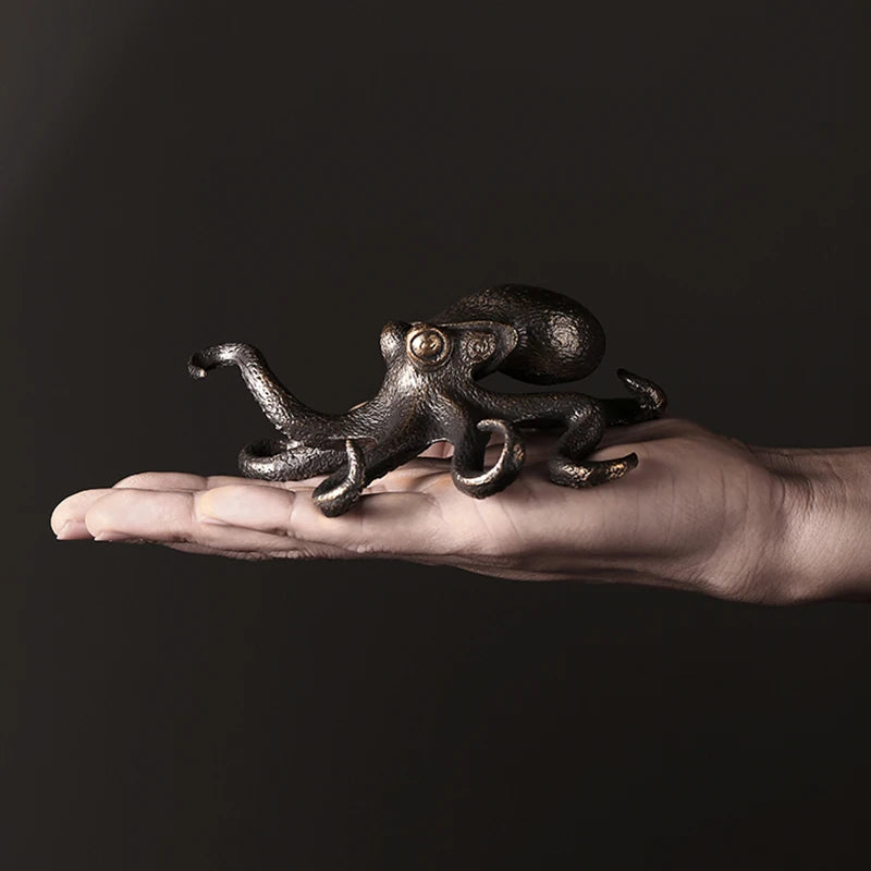Hand holding a decorative metal octopus against a dark background