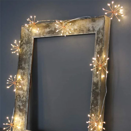Dandelion-shaped string lights draped around a rustic, empty picture frame.