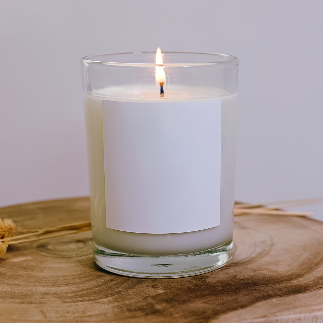 Candle in a glass jar with a white label on a wooden surface