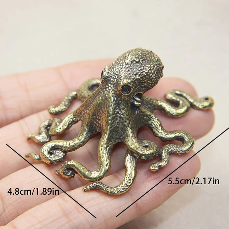 Bronze octopus figurine held in a hand with measurements indicated