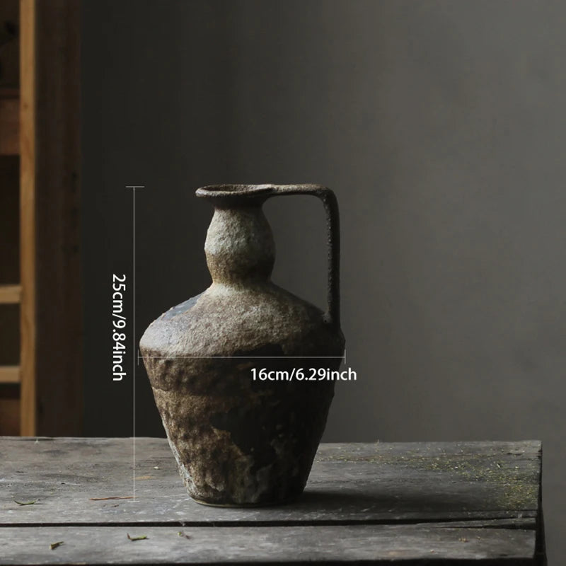 Wabi Sabi Ceramic Vase with dimensions labeled: 25cm/9.84inch height and 16cm/6.29inch width. The vase is rustic and textured with a handle, displayed on a wooden table.