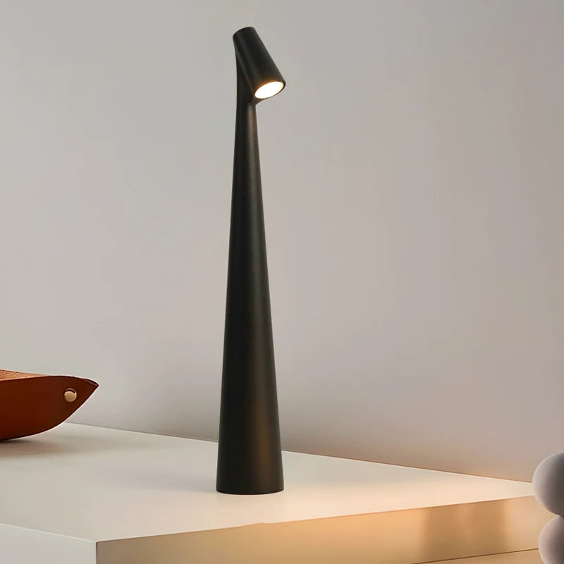 A sleek, modern, black lamp with a narrow, tall base and a small light at the top, standing on a white surface.