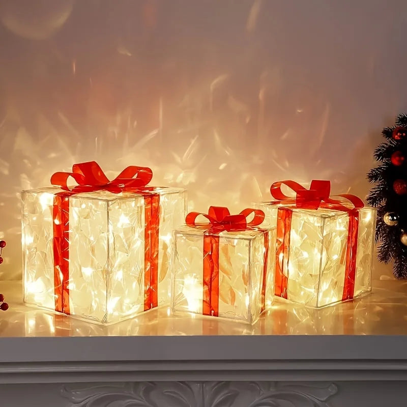 Three clear, glowing gift boxes with red ribbons sit on a mantelpiece next to a small Christmas tree.