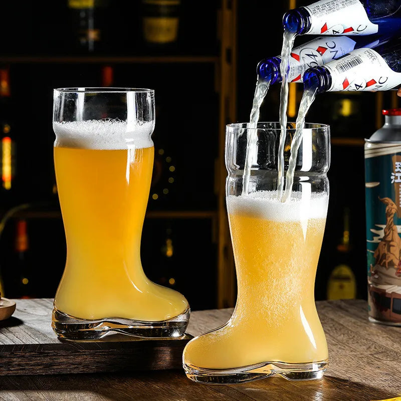 Two beer boot glasses, one being filled with beer from three bottles, on a wooden surface in a dimly lit bar setting.