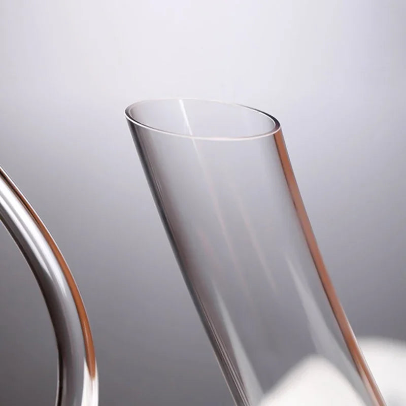 A close-up of the angled, hand-cut opening of a glass wine decanter.