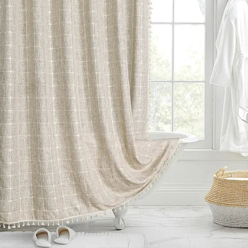 Beige curtain with tassels in a room with a window and white floor.