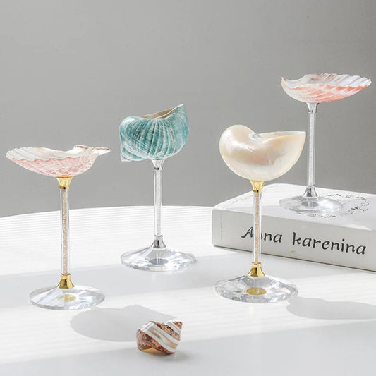 Set of four decorative shell-shaped glasses on a white surface with a gray background.