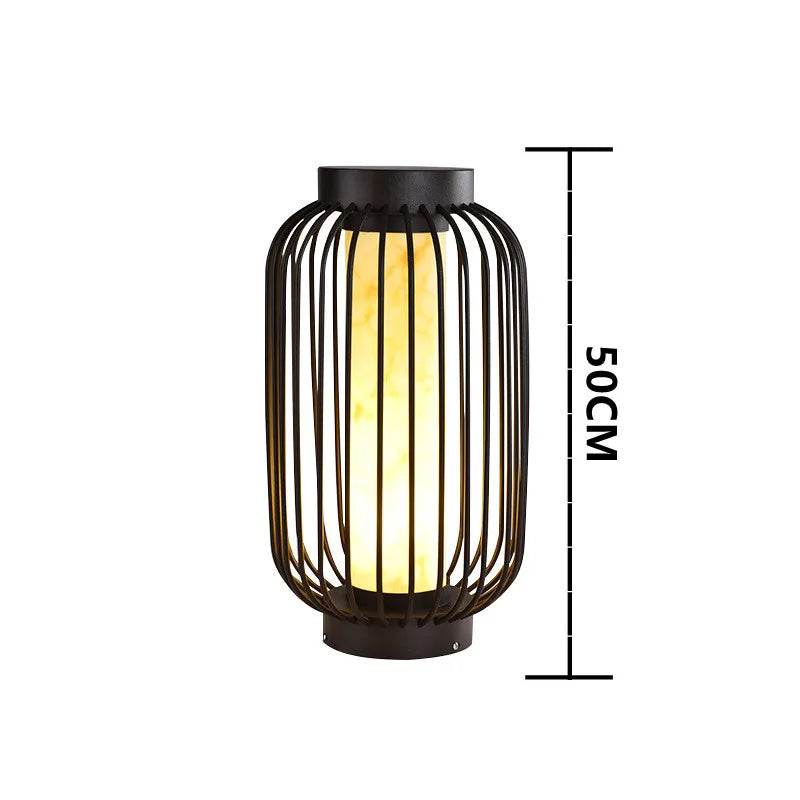 A diagram shows the dimensions of a modern cylindrical outdoor lantern with a dark metal frame and a warm internal light as 50 cm in height. The lantern has vertical slats forming its structure and stands against a plain white background.