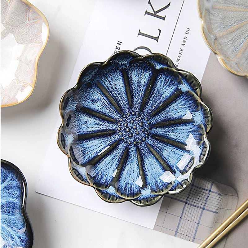A close-up of a blue, flower-shaped condiment dish with a sunburst pattern.