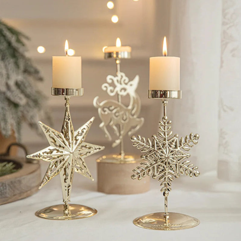 Three lit candles in gold star, reindeer, and snowflake Christmas candle holders.