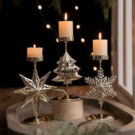 Three lighted candles in festive gold Christmas candle holders.