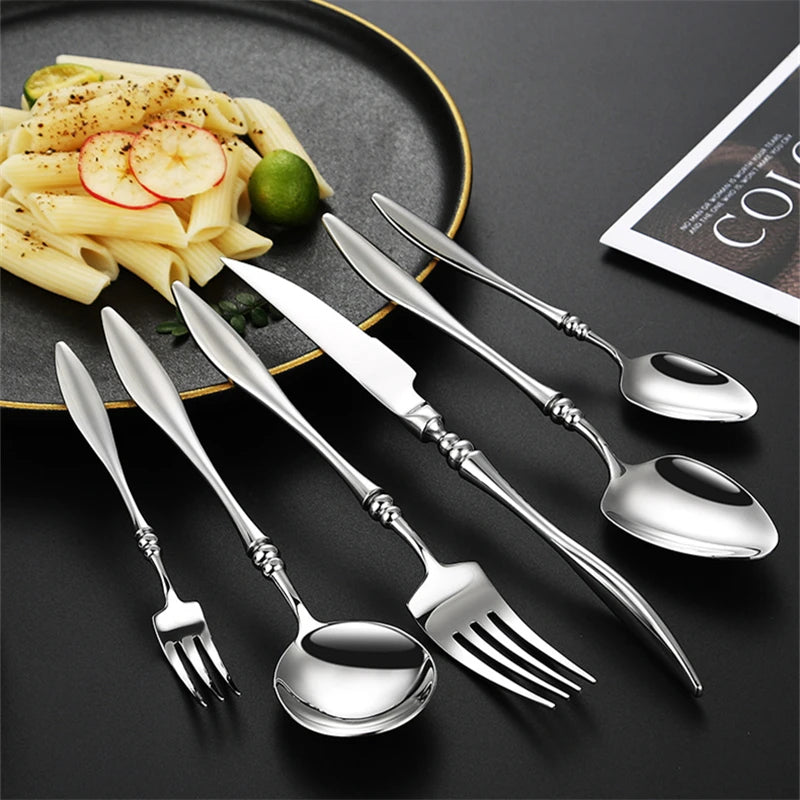 A full set of silver utensils with a plate of pasta.