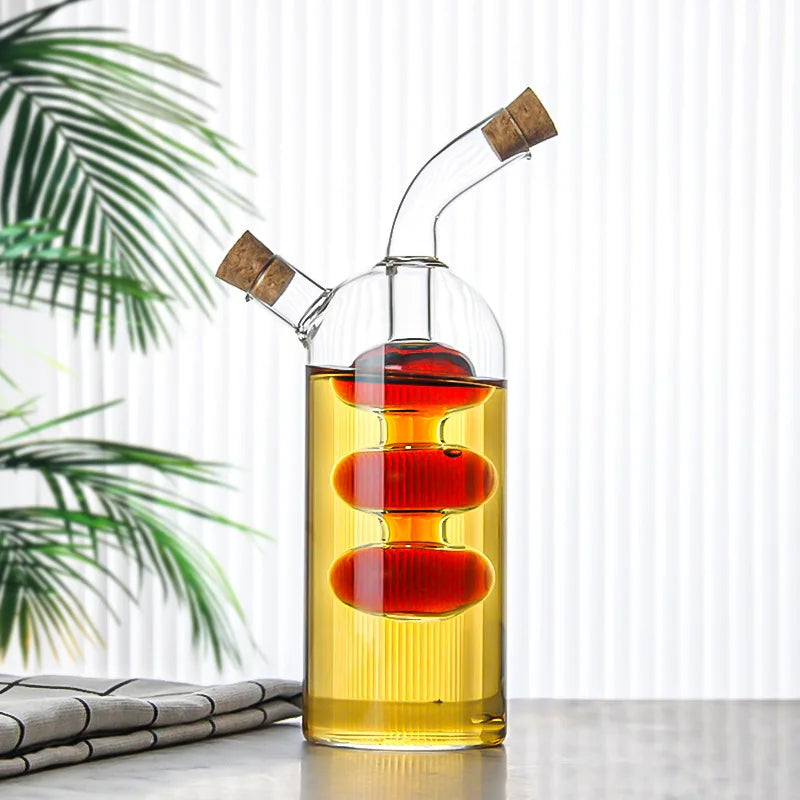 Glass oil and vinegar dispenser with cork stoppers on a white surface with a plant in the background