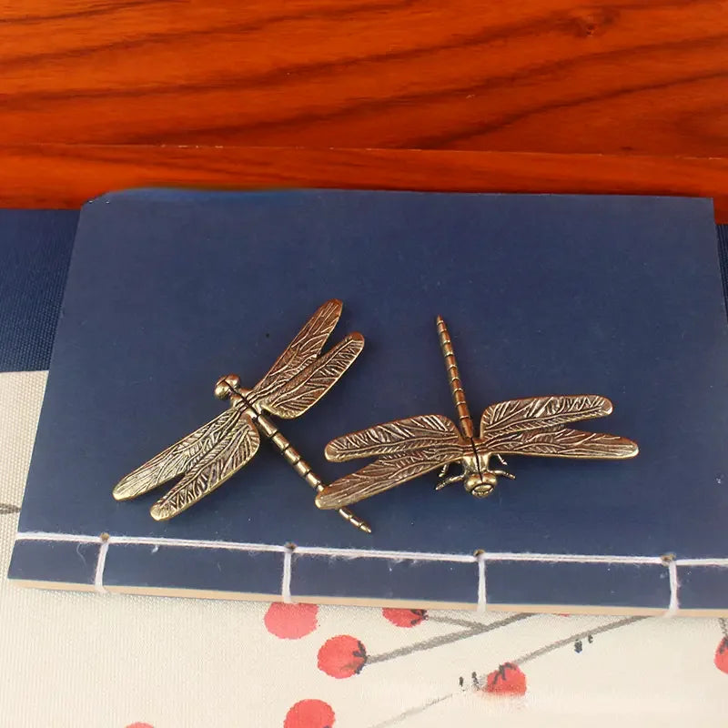 Bronze dragonfly earrings on a blue card with a red fabric background
