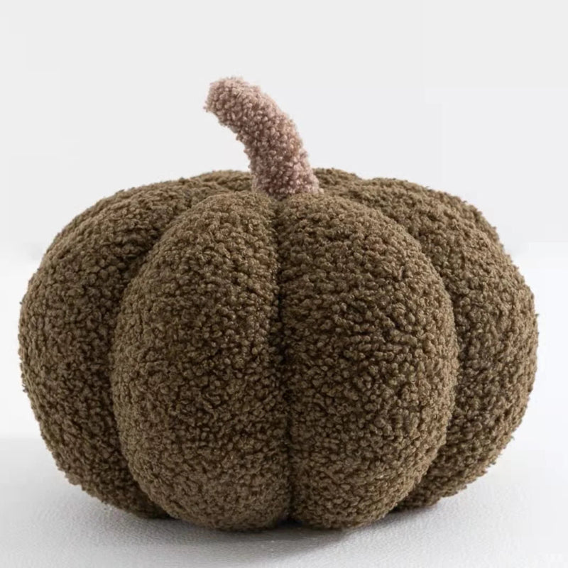 A fuzzy, dark brown pumpkin-shaped pillow with a light brown stem.