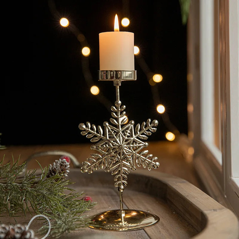 Lit candle in a gold snowflake candle holder with pine decorations.