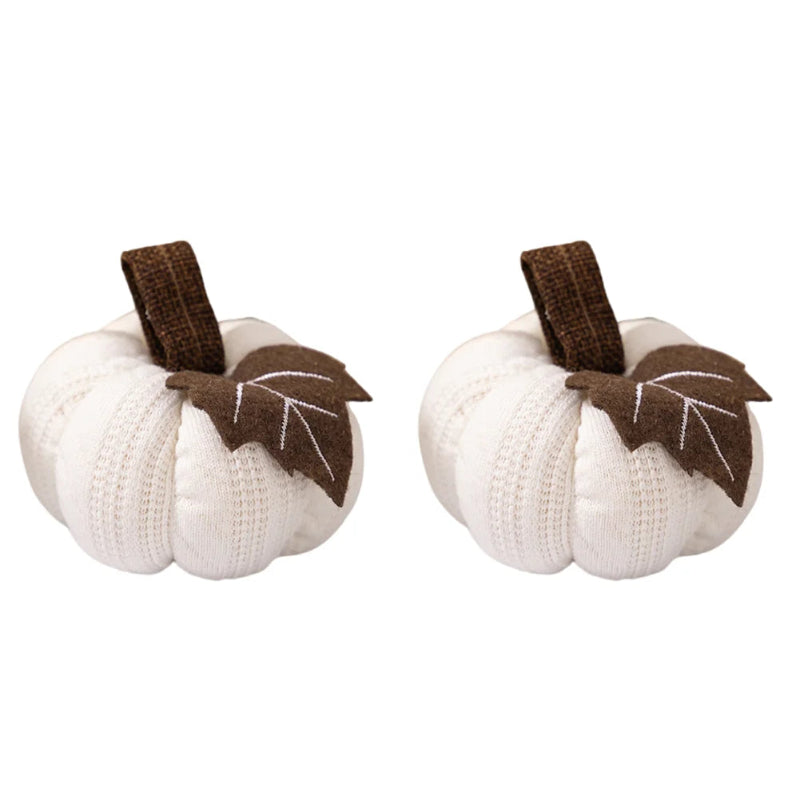 Two identical white knitted pumpkins, each with a brown stem and a brown fabric leaf, isolated on a white background.