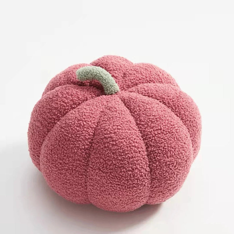 A fuzzy, dark pink pumpkin-shaped pillow with a light green stem.