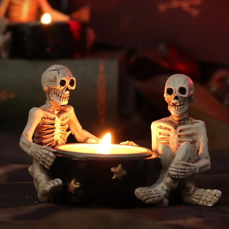 Two skeletons sit around a lit candle in a dark setting.