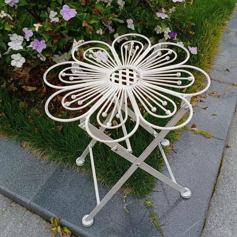 White metal garden table with decorative design on a patio