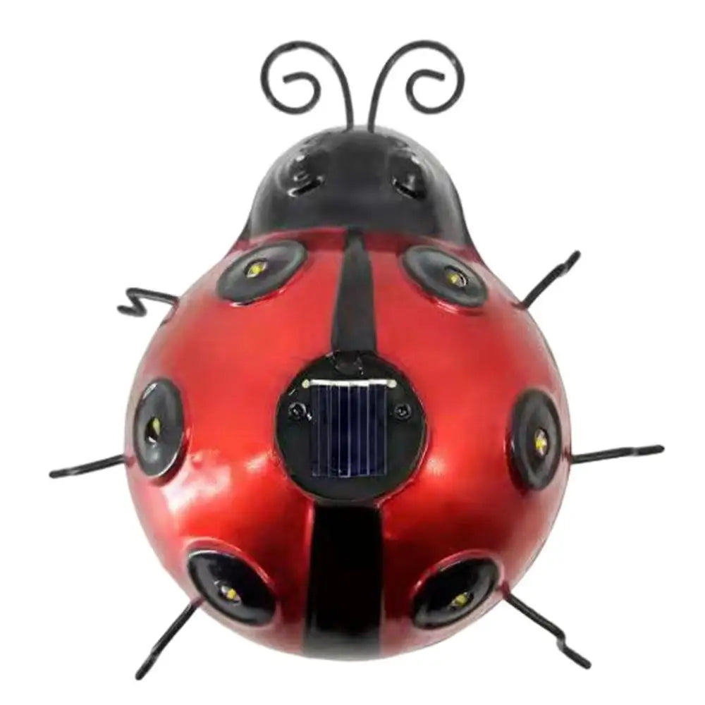 A decorative red and black metal ladybug with a small solar panel on its back is shown against a white background. It has black antennae and six black legs, with small lights embedded in its spots.