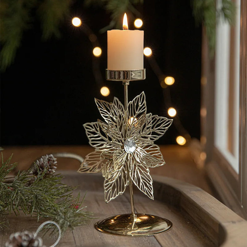 Lit candle in a gold poinsettia-shaped candle holder.