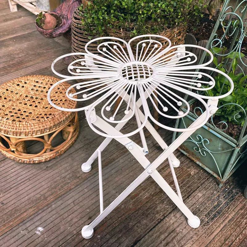 White metal folding stool with floral design on a wooden deck