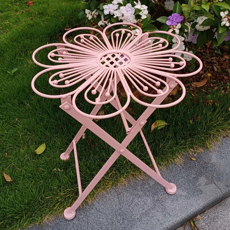Pink metal garden table with decorative design on grass