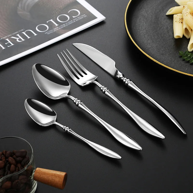 A set of silver utensils, with a pasta dish and coffee beans in the background.