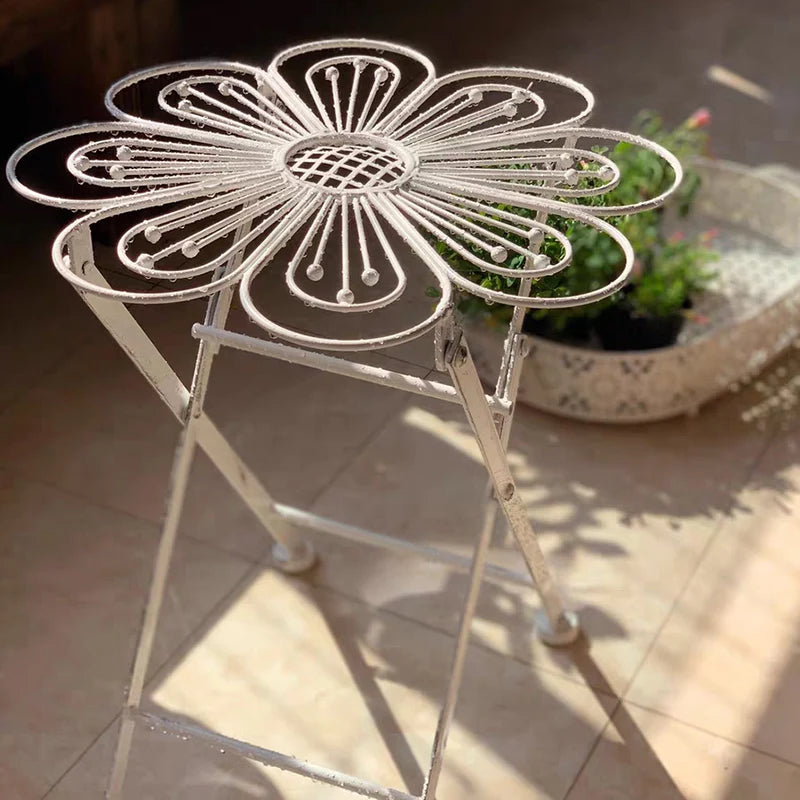 Decorative metal table with flower design on a tiled floor