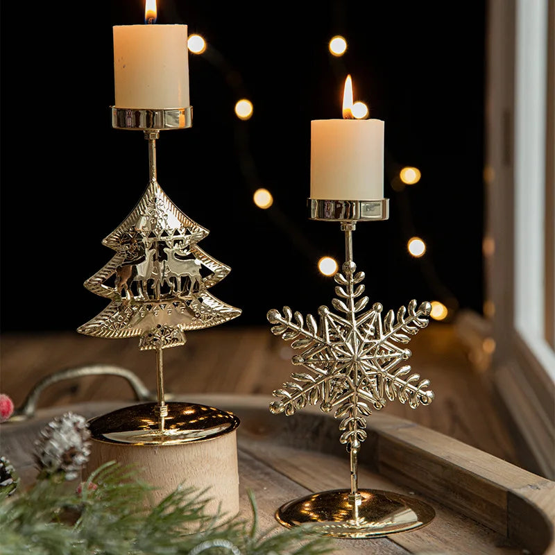 Two lit candles in gold Christmas tree and snowflake candle holders.