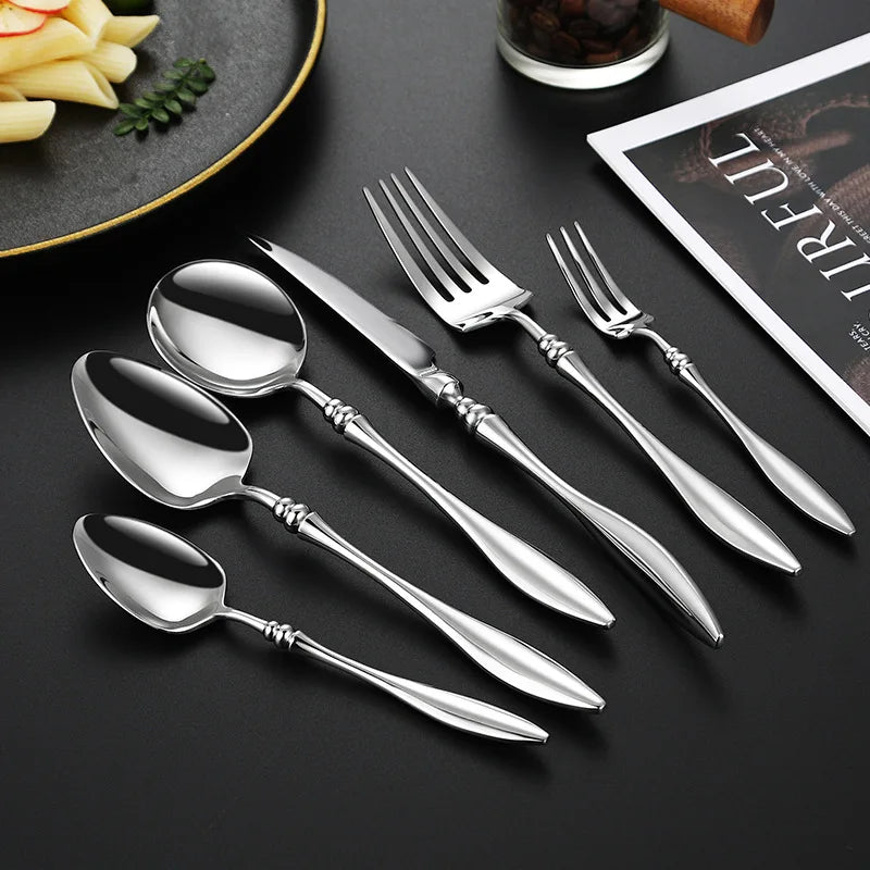 A set of silver utensils, with a pasta dish in the background.