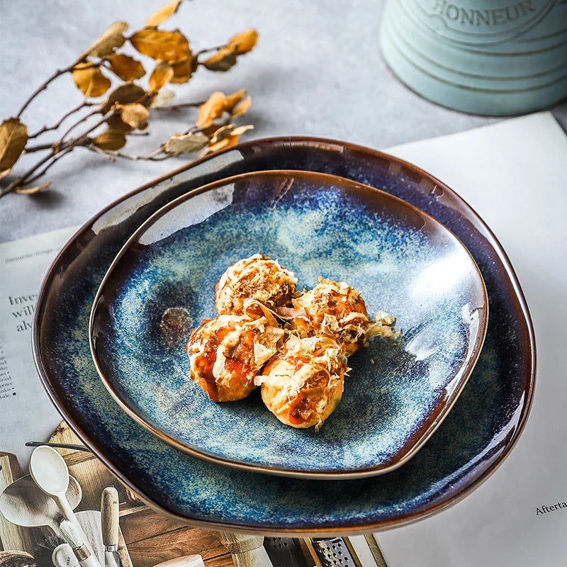 Blue ceramic plate with food on a table with a cup and utensils.